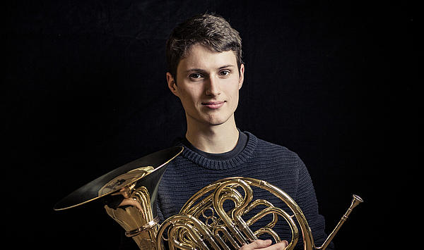 Das Bild zeigt einen jungen Mann mit einem Horn. Das Bild zeigt einen jungen Mann mit einem Horn.